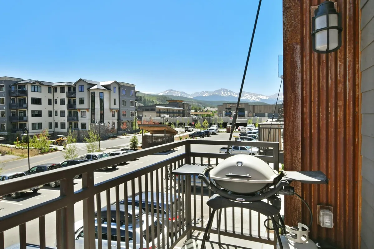 This exterior-facing image spotlights a private balcony equipped with a grill, comfortable seating, and panoramic mountain vistas. It shows how indoor living effortlessly extends outside, perfect for barbecues or soaking up alpine air.