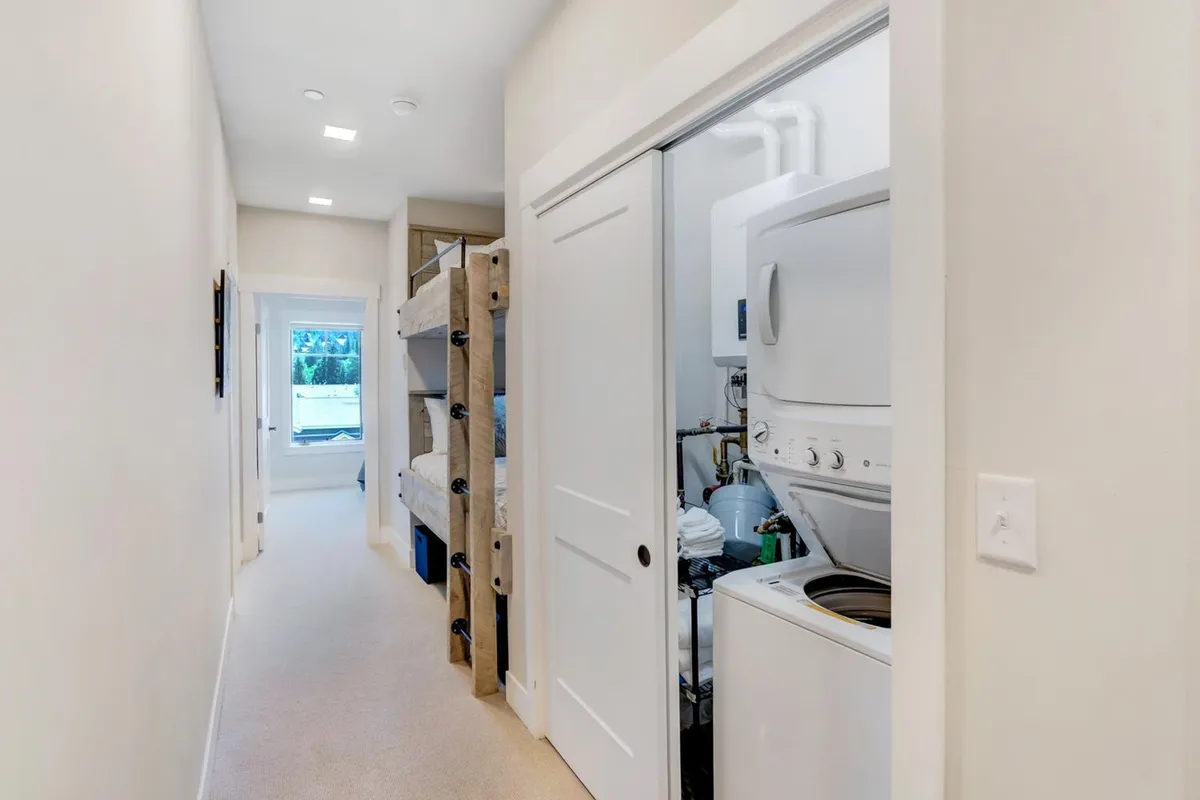 This interior image features a practical laundry area integrated within a family-friendly bunk bed space, with a window offering natural light. The presence of both laundry machines and bunk beds indicates a space tailored for family convenience and day-to-day comfort.