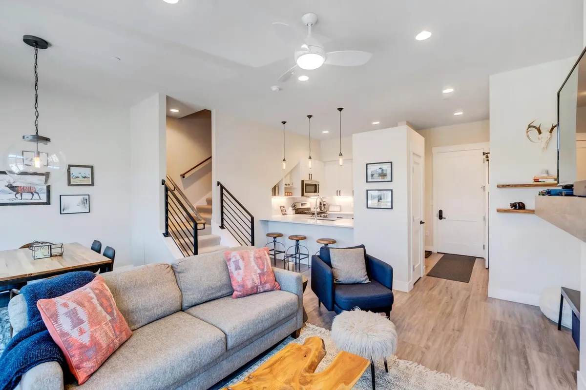 This interior photo captures the open-concept living area, clearly showing the sofa, dining table, kitchen island, and a staircase. The layout is perfect for socializing, with seamless transitions between spaces where people can relax, dine, and gather together.